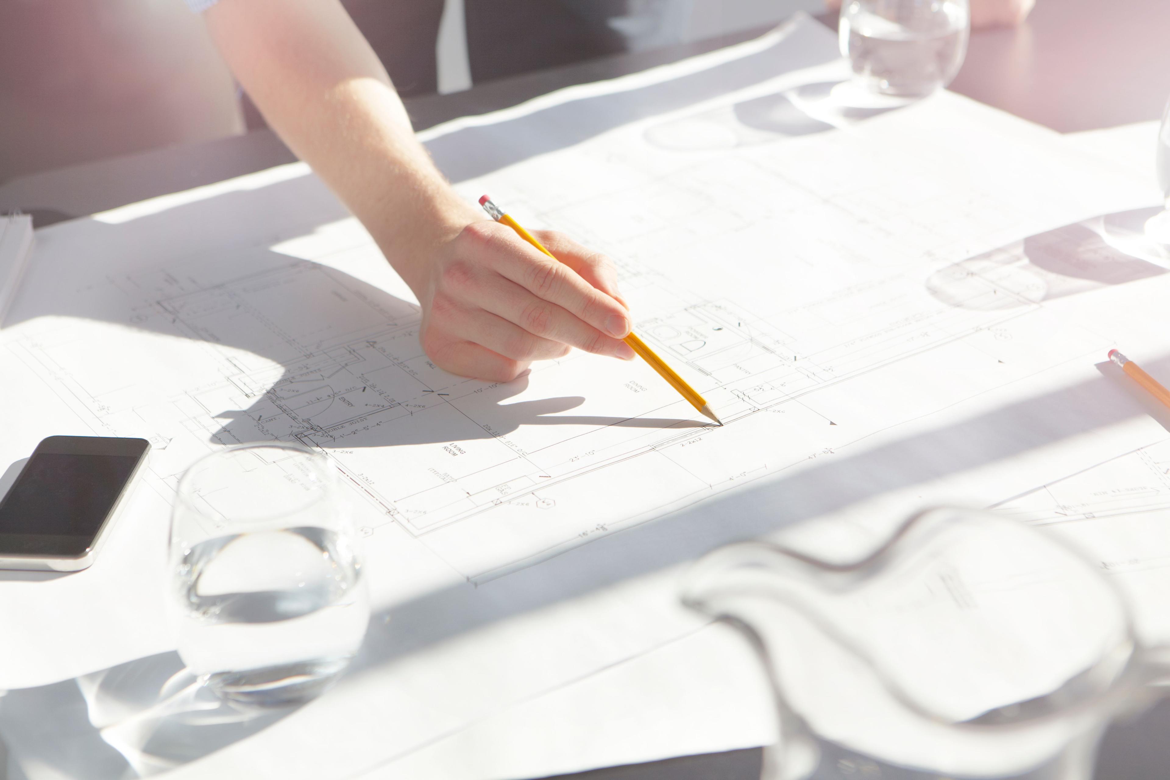 Designing construction plans with pencil on a brightly lit desk