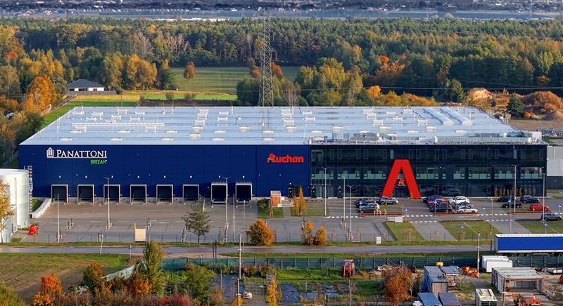 Widok magazynu Auchan w Wilczej Górze, z logotypami Panattoni i Auchan.
