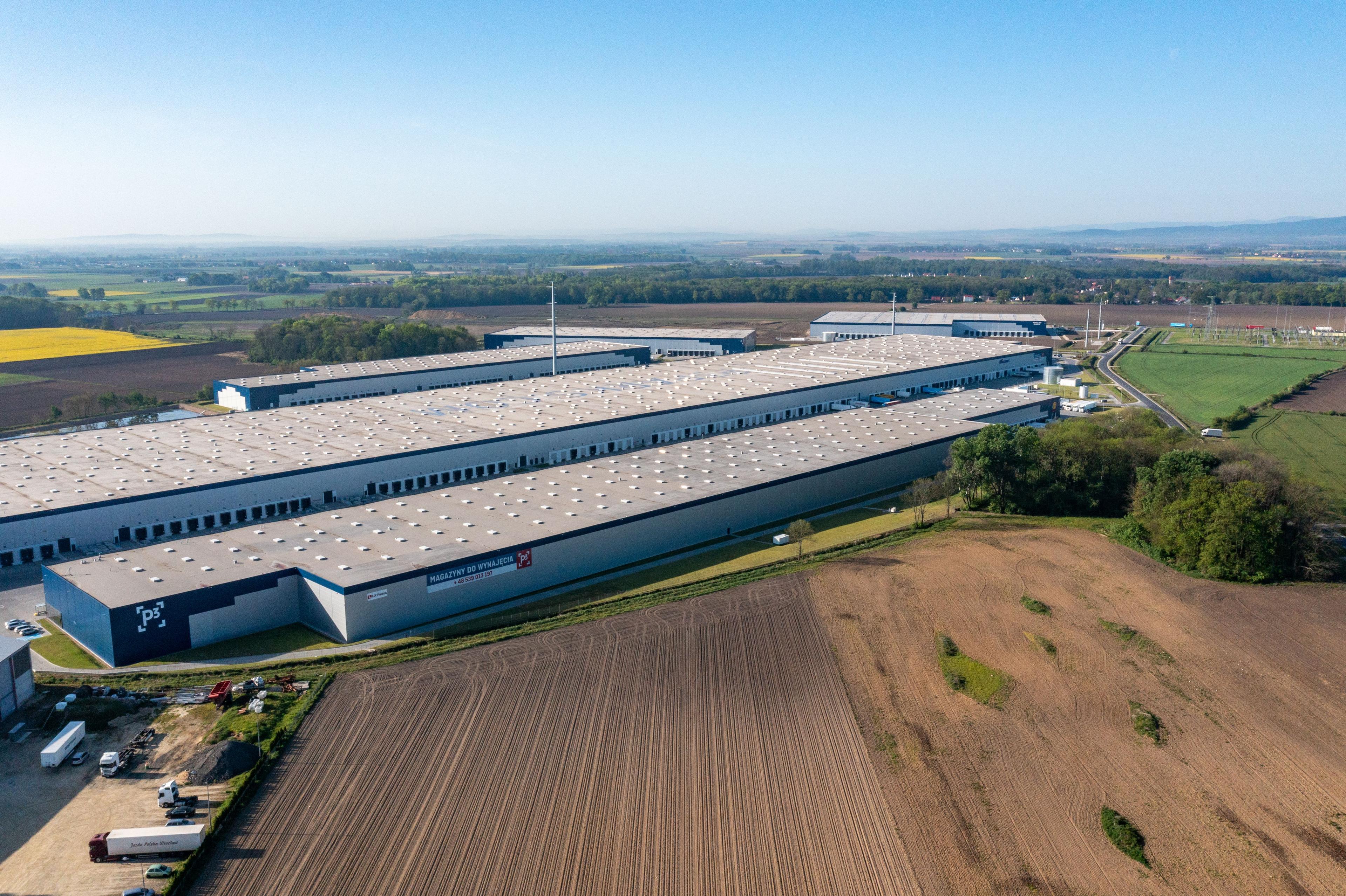 Panorama centrum logistycznego ID Logistics w parku P3 Wrocław II, otoczonego polami uprawnymi.