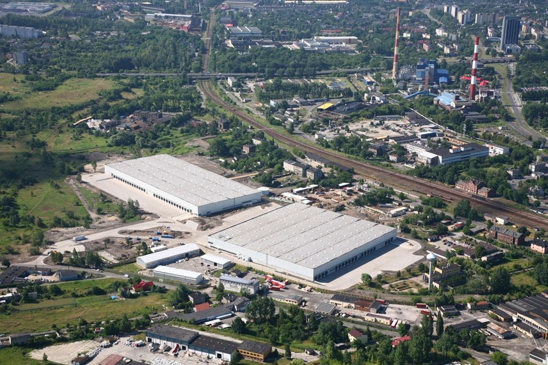 Zdjęcie lotnicze przedstawia dwa obiekty magazynowe Park Będzin II, zlokalizowane w pobliżu torów kolejowych, w miejscowości Będzin.