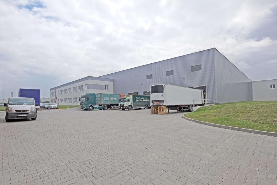 Zdjęcie przedstawia plac manewrowy MLP Tychy, w tle trwający załadunek tirów oraz widoczna część biurowa budynku ,,B3’’.