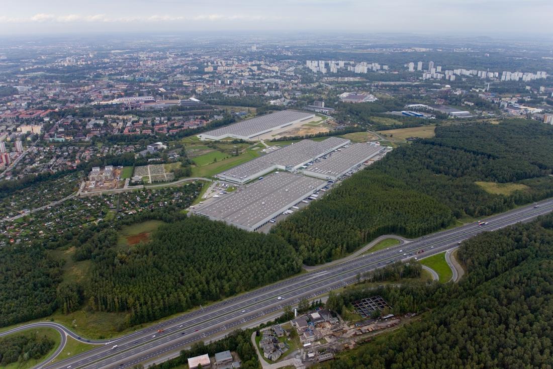 Zdjęcie ukazuje samochody na parkingu Prologis Park Chorzów, w tle obiekt magazynowo-biurowy.