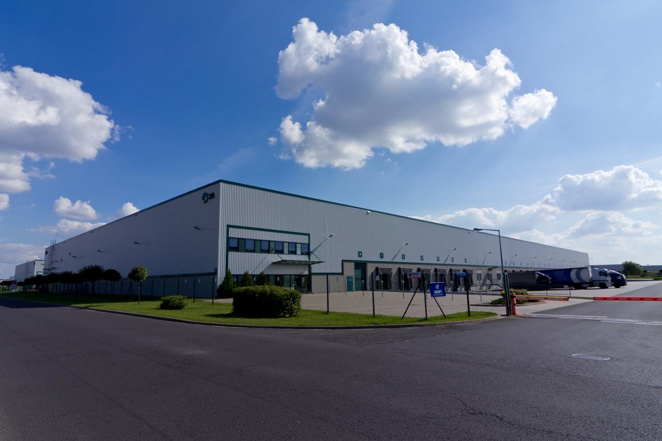 Zdjęcie ukazuje bramę wjazdową Prologis Park Poznań I, w tle budynek magazynowy ''DC 3''.