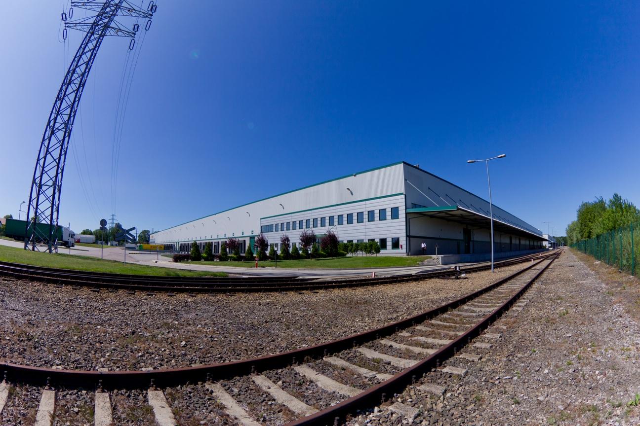 Zdjęcie panoramiczne ukazuje bocznicę kolejową Prologis Park Teresin, w tle budynek magazynowy.
