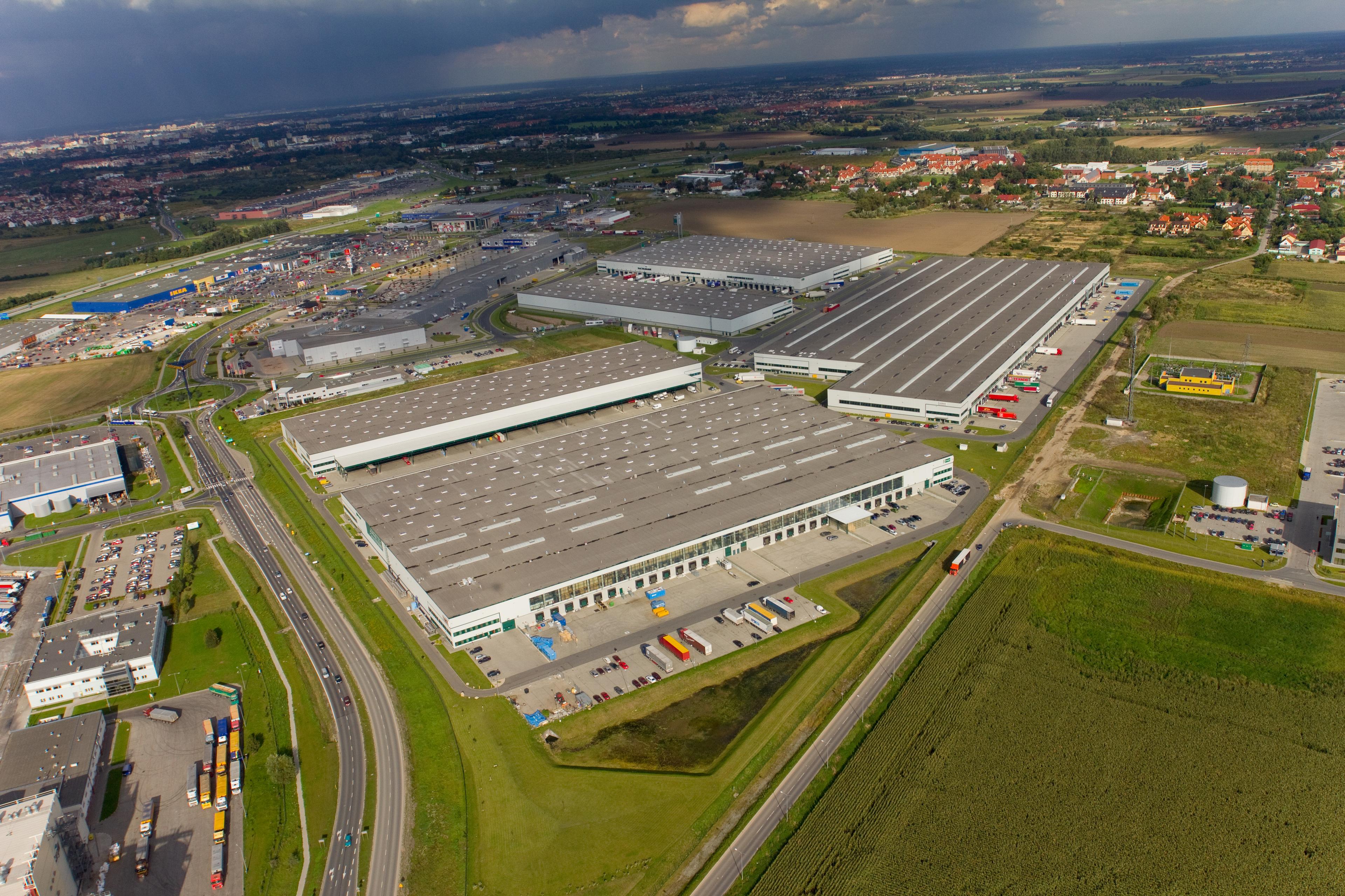 Zdjęcie lotnicze prezentuje 8 budynków magazynowych Prologis Park Wrocław I w zachmurzony dzień.