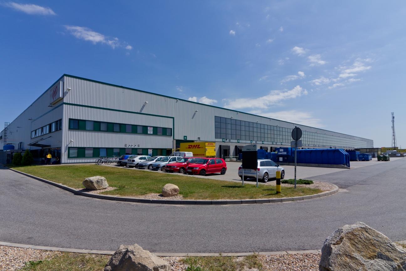 Zdjęcie ukazuje samochody na parkingu oraz obiekt magazynowy Prologis Park Wrocław I.