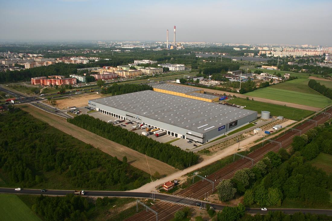 Zdjęcie lotnicze ukazuje obiekt magazynowy SEGRO Business Park Łódź, zlokalizowany w pobliżu torów kolejowych, na obrzeżach Łodzi.