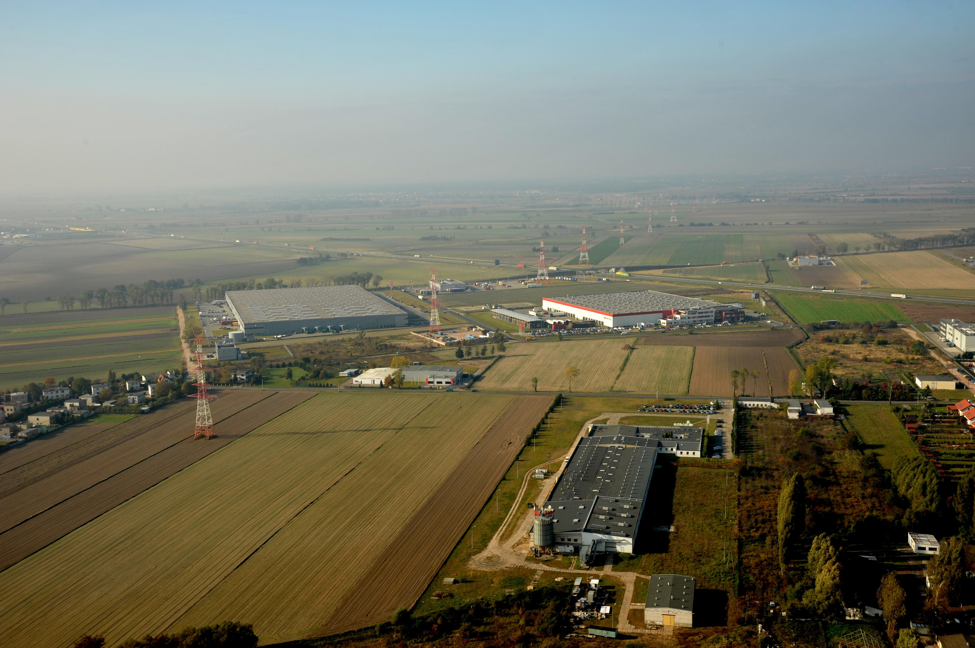 Zdjęcie lotnicze prezentuje obiekty magazynowe Segro Logistics Park Poznań, w tle autostrada A2.