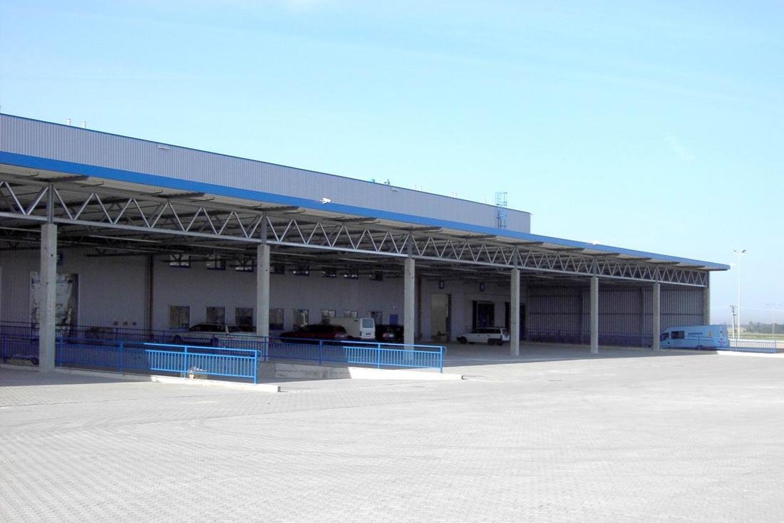 Zdjęcie prezentuje plac manewrowy Segro Logistics Park Stryków, w tle 6 samochodów zaparkowanych pod dachem magazynu.
