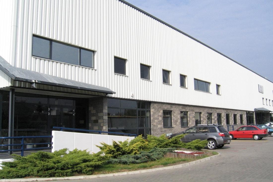 Zdjęcie przedstawia parking oraz budynek biurowy Warsaw Distribution Center.